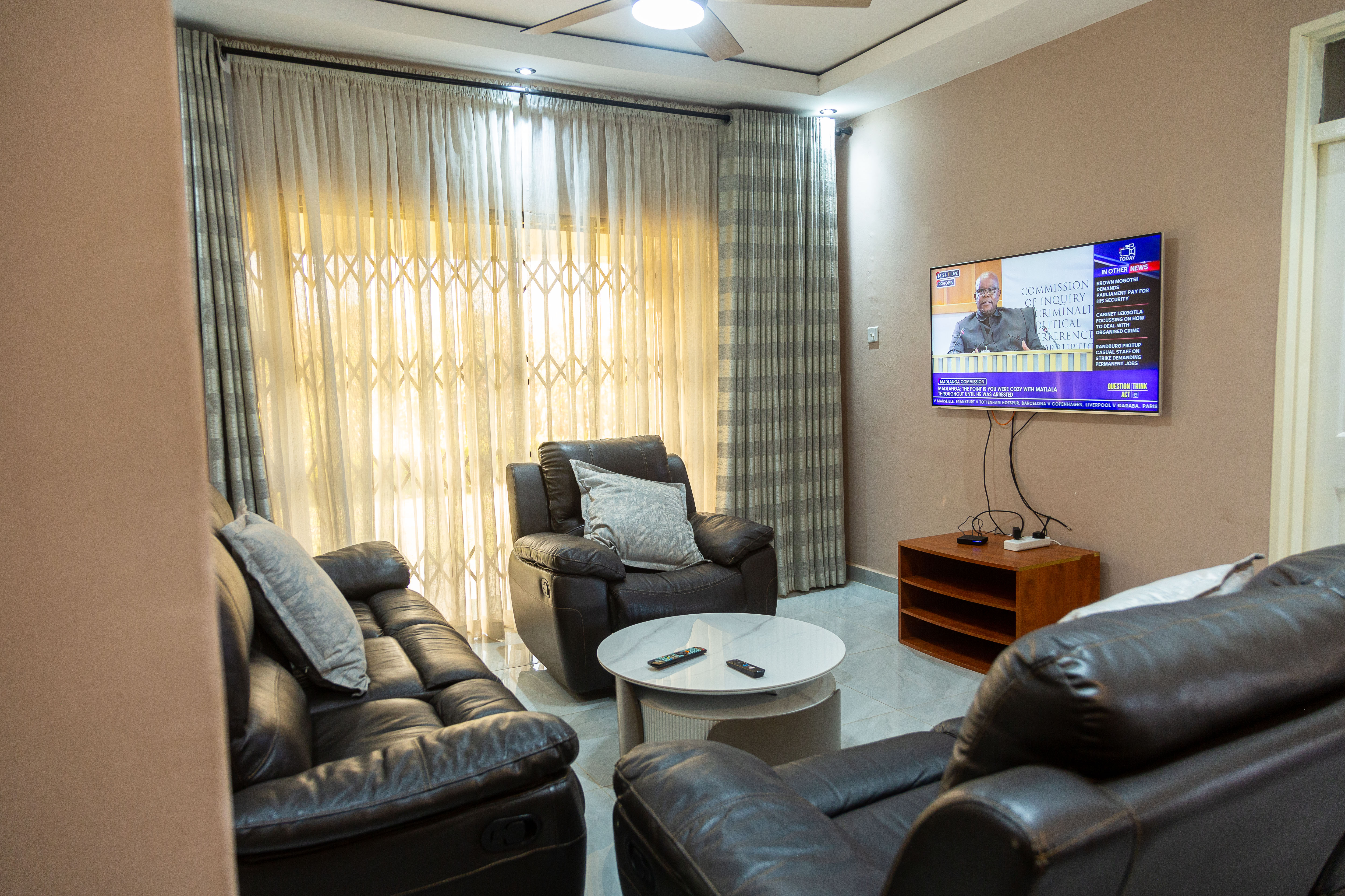 Living room with leather sofas, armchairs, and a wall-mounted TV