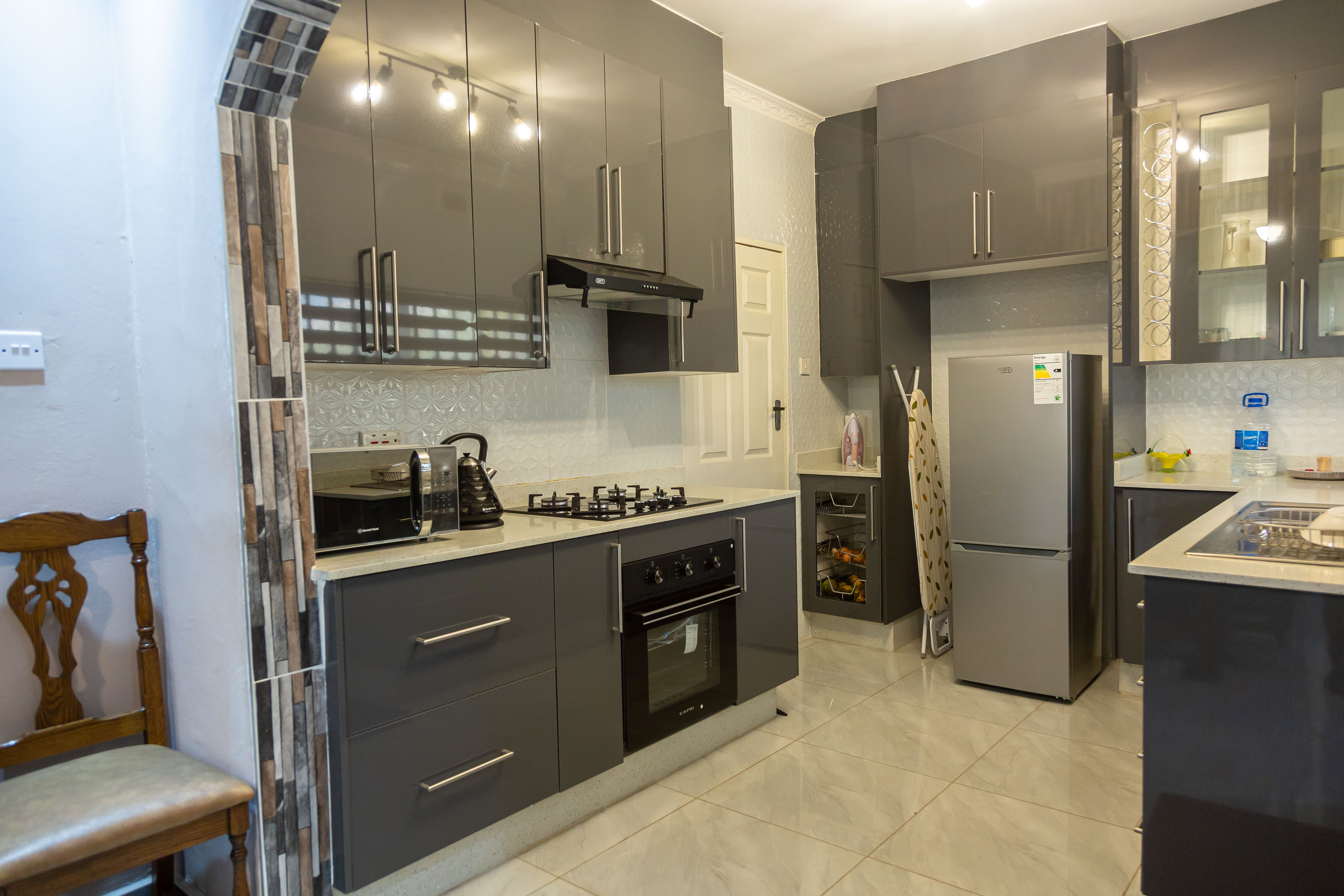 Kitchen with grey cabinets, gas stove, oven, and refrigerator