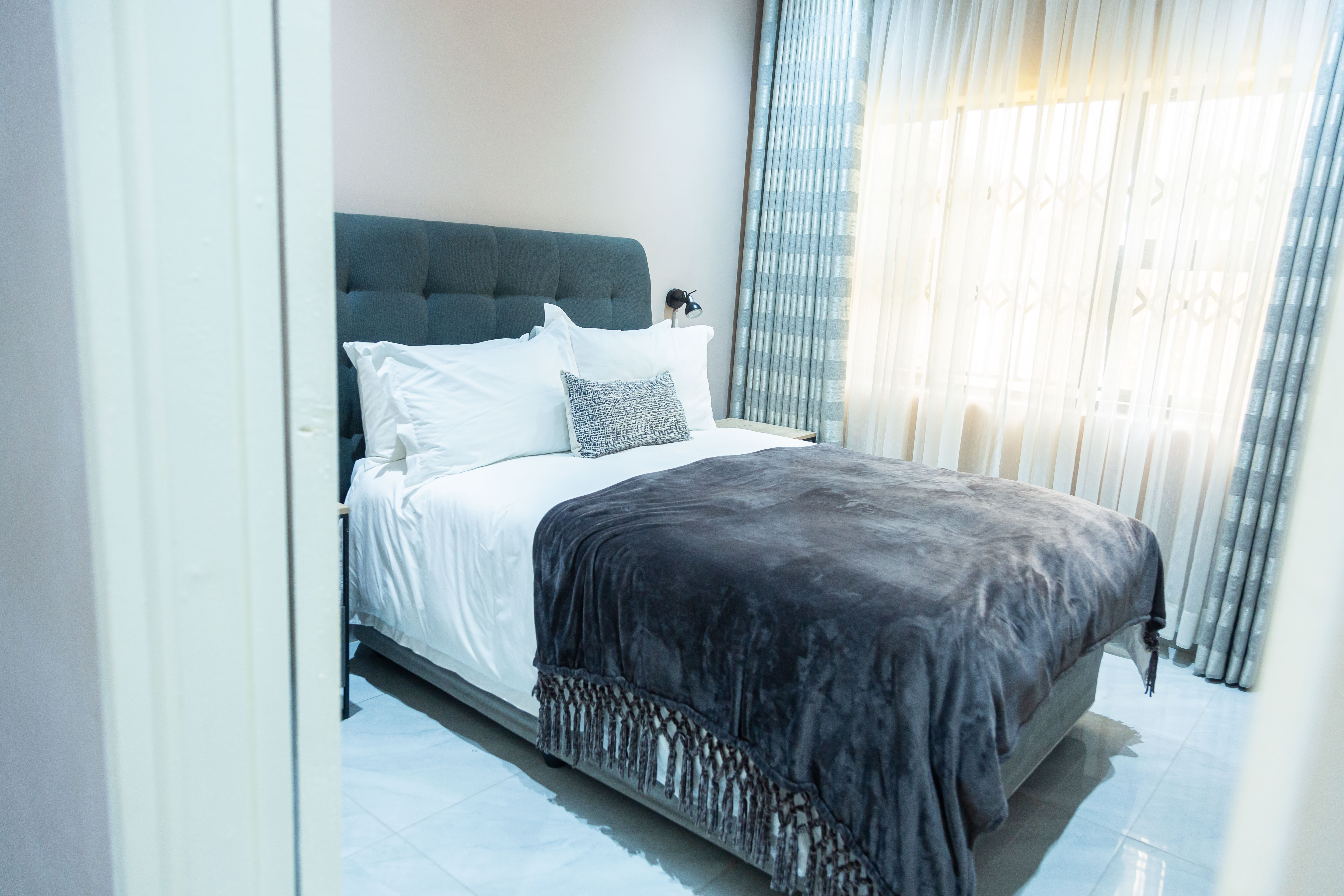 Bed dressed in white linen with a dark throw