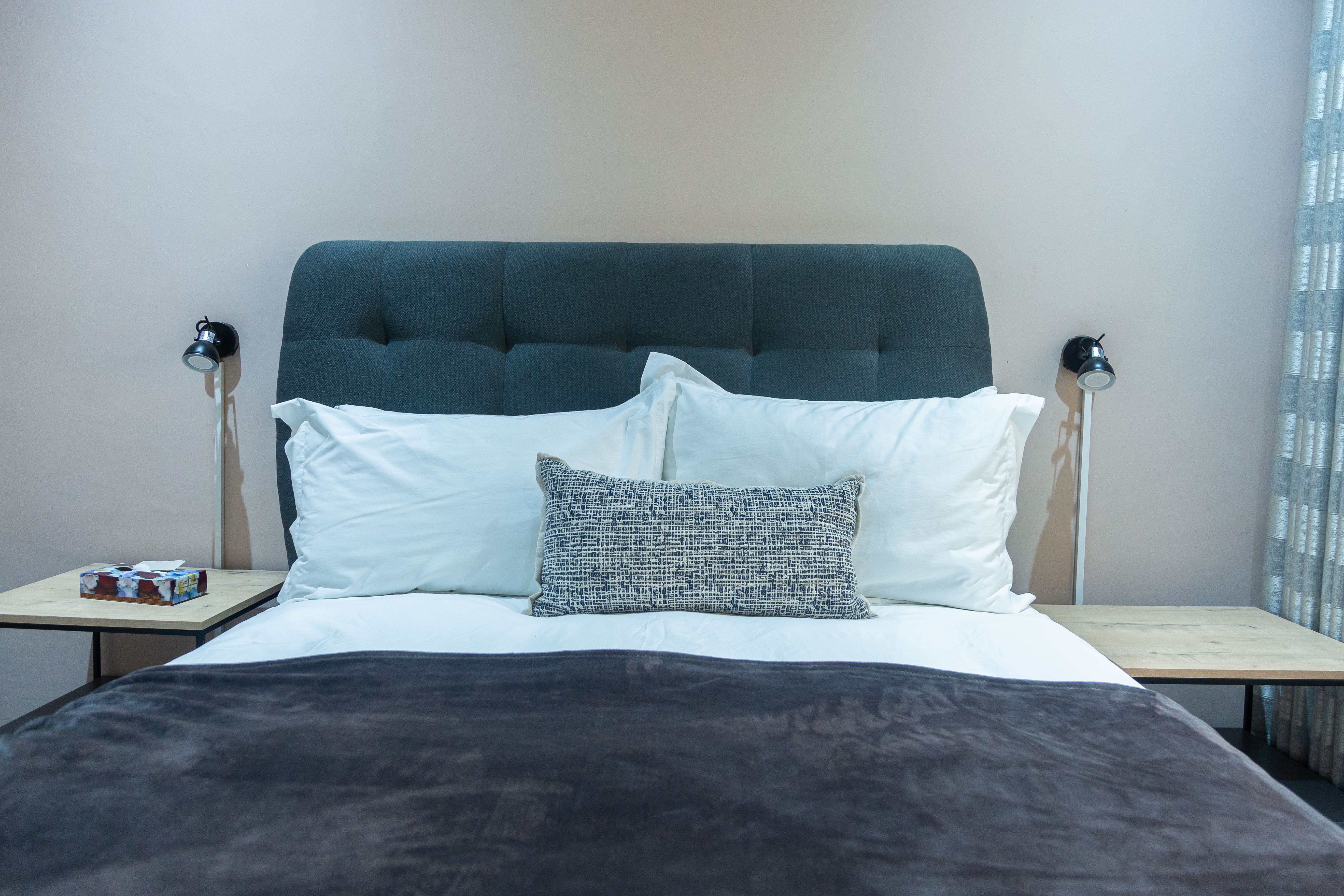 Bed with a grey tufted headboard and matching bedside lamps
