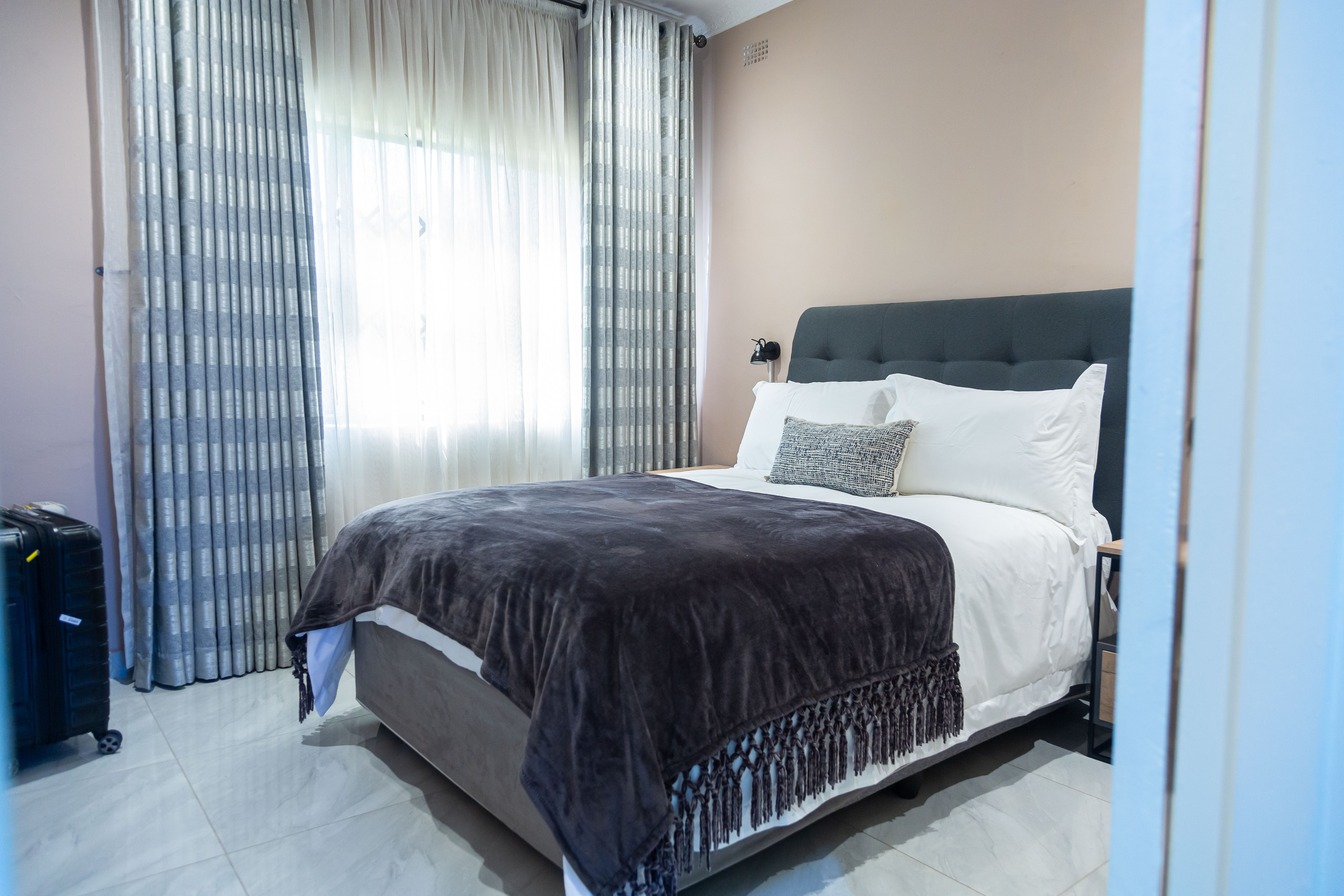 Bedroom with a dressed bed, curtains, and bedside lamp